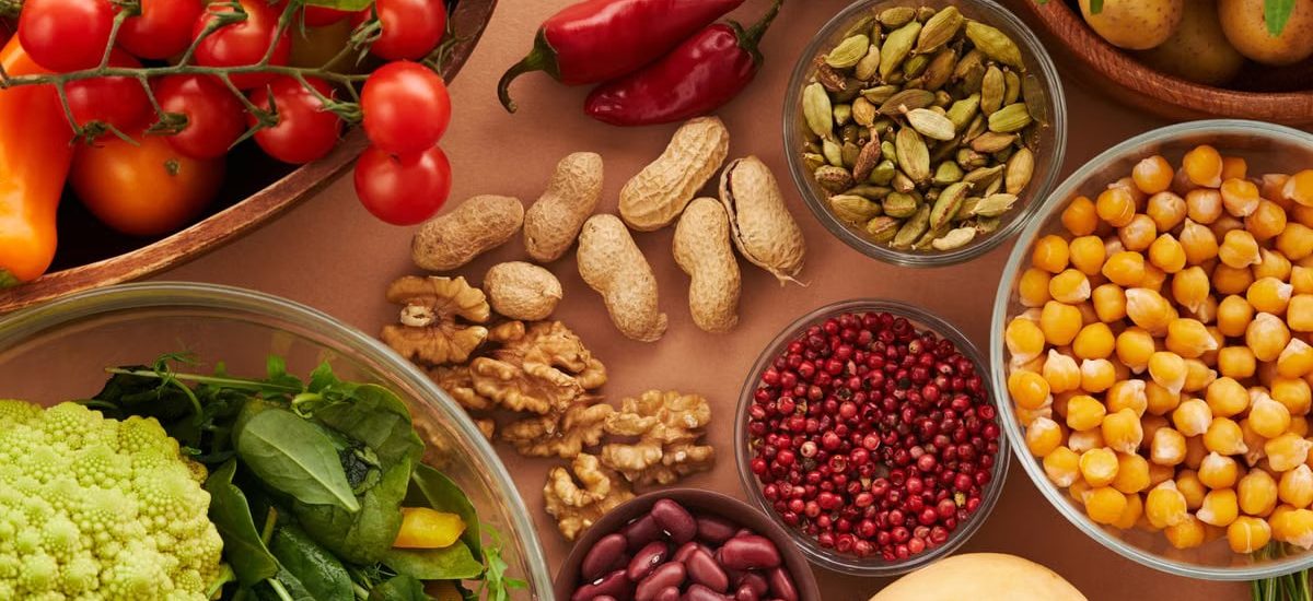 Explore a colorful assortment of healthy ingredients, featuring vegetables, nuts, seeds, and spices in a top view layout.